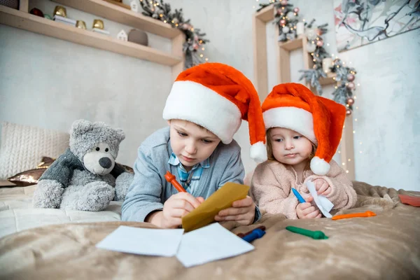 the boy writes to Santa Claus. Christmas family evening. New Year presents. Decorated bright living room