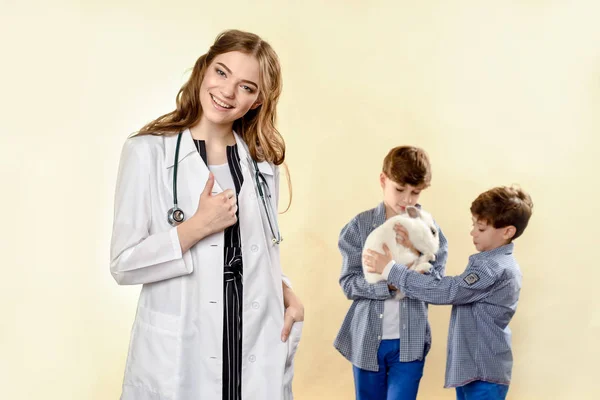 Doctor vet doctor examines a pet. Sick rabbit. inoculation to animals. Laughing boy getting back cute pet rabbit from veterinary at pets' clinic. In the studio on a light background — 图库照片