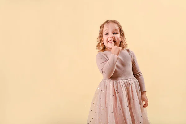 Menina loira e feliz, emocionalmente surpreendida. Em um fundo rosa no estúdio em um vestido cheio elegante de tule. Cabelo encaracolado. Espaço de cópia — Fotografia de Stock