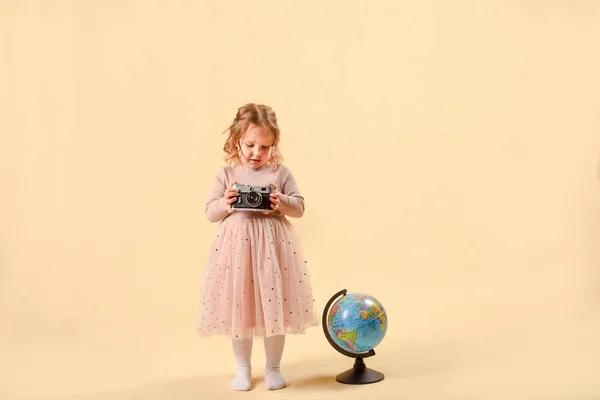Ler söt skolflicka. skrattande liten flicka med en glob i studion på en rosa bakgrund. Begreppet att studera i skolan, eller resa — Stockfoto