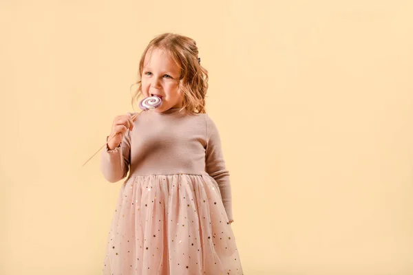 Bebé com doces. Vestido elegante rosa. Férias ou aniversário. Doces na mão. em um fundo leve no estúdio . — Fotografia de Stock