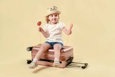 Anne, kız ve bavullar. Bayanlar tuvaletinde oyna. Denize yolculuk. Dinlenme ve yaz tatili. Seyahat konsepti. Stüdyoda hafif bir arka planda