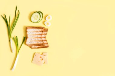 Sandviç yapmak için gerekli malzemeler. Taze soğan, şampiyon mantarı, beyaz ekmek, peynir ve yumurta. Vejetaryen burger. Sarı arkaplan, üst görünüm, kopyalama alanı.