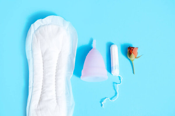 Женская интимная гигиена на синем фоне. Санитарная прокладка, мазок или чашка. выбор современной женщины. Красная роза. концепция менструального цикла у женщин

