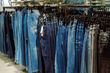Bir sıra asılmış kot pantolon. Bir alışveriş merkezinde kot pantolon mağazası. Denim satışları. Mavi pantolon. Kadın alışverişi. Moll!.