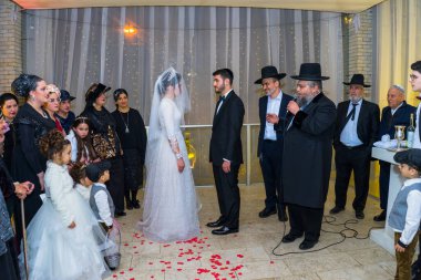 Rehovot, Israel - 11.01.2019. Rabbi blessing Jewish bride and groom in Jewish chasid wedding clipart