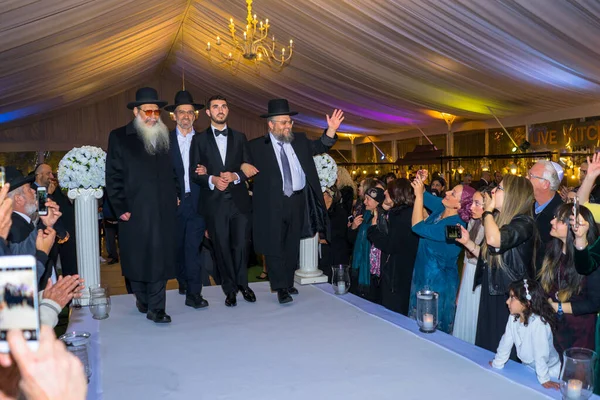 Rehovot, Israel - 11.01.2019. Rabino levando noivo judeu para Chuppah em casamento chasid judaico com convidados felizes — Fotografia de Stock