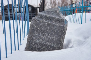 Gotik Alman harfleriyle terk edilmiş bir mezar taşı.