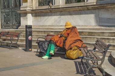 Yeşil pantolonlu ve ayakkabılı dilenci.
