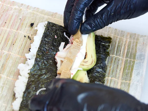 Sishi Roll hazırlayan siyah eldivenli aşçıların yakın plan fotoğrafı.