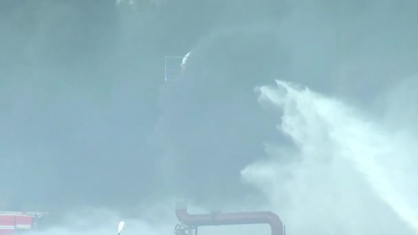 一个燃料箱和一个反应堆在燃烧 消防员正在用软管 烟雾和烟尘的泡沫溶液扑灭大火 这是一场环境灾难 — 图库视频影像