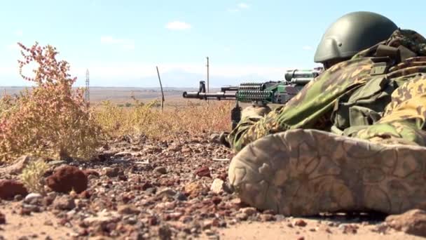 在军用头盔瞄准机枪 躺在沙滩上埋伏 — 图库视频影像