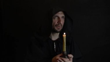 sakallı bir keşiş mum ışığında bir dua okur, bir mum alevi 44 sways