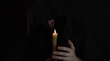 sakallı bir keşiş mum ışığında bir dua okur, bir mum alevi 11 sways