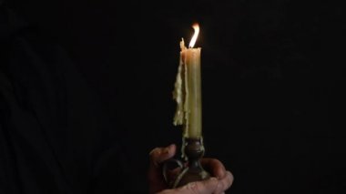 sakallı bir keşiş mum ışığında bir dua okur, bir mum alevi 9 sways