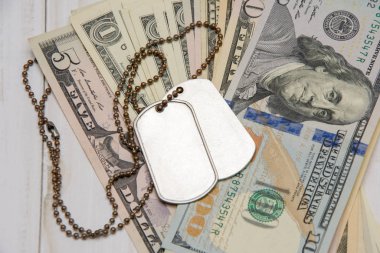 Askerlerin askeri jetonları dolar banknotlarının üzerinde. Kavram: Yaşayan askerlerin, emekli aylıklarının, paralı askerlerin maliyeti.