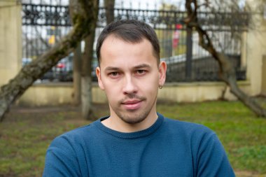 30 yaşlarında orta yaşlı bir gencin sokak portresi doğrudan kameraya bakıyor. Asker portresi ya da üniformasız bir subay, tatilde..