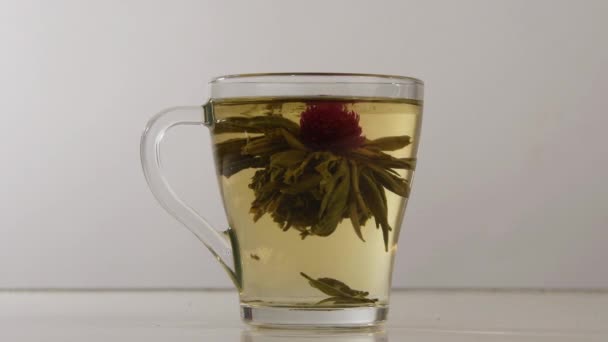 Le bourgeon de thé parfumé chinois lié s'ouvre dans une tasse transparente .