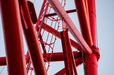 Mavi gökyüzüne uzanan kırmızı çelik boruların bağlantısı metal yapıları destekliyor..