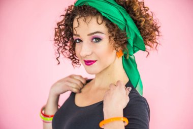 30-35 yaşlarında kıvırcık siyah saçlı genç bir kadın kameraya bakıyor, yüzünde mutluluk duyguları, beklenti içindeki neşe.