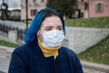Şehirde bulaşıcı hastalık tehlikesi var. Sokakta virüs bulaşma riski var. Tıbbi maskeli bir kız sokakta yürüyor. Önlemler, hastalıkların önlenmesi.