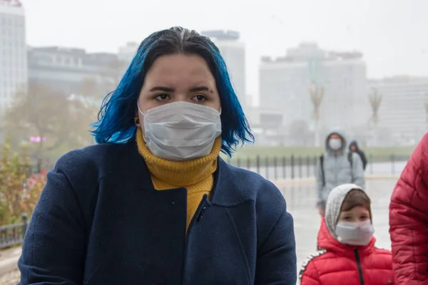 Danger of infectious diseases in the city. Risk of virus infection in the air on the street. Passers - by in medical masks are walking down the street. Precautions, prevention of diseases.