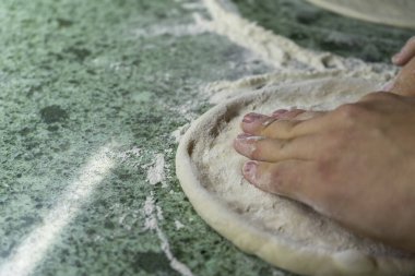 The hands of the chef rolled out the pizza dough on the kitchen table, close-up, clipart