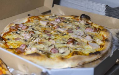 Sosis, peynir ve jambon dilimli hazır pizza müşteriye teslim edilmesi için bir kutuya konur.