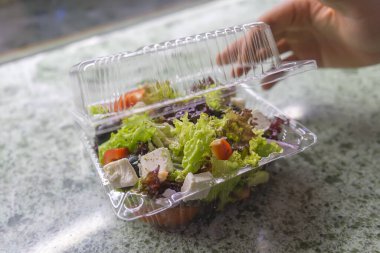 Plastik bir kapta Yunan salatası, paket yemek.