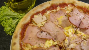 Peynirli, soslu, jambonlu, pastırmalı, füme tavuklu ve yumurtalı Karnos pizzası masada.