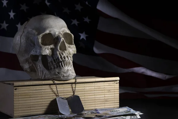 Human skull on the background of the American flag, dollars and military medallions. Concept: military special operations, The price of victory, dead soldiers, benefits and pensions for families