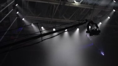 Operatörün vincindeki kamera ışıltılı projektörlerin arka planında uçuyor..