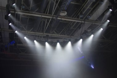 Sahne ışıkları. Performansın sahnesi projektörlerle aydınlatılıyor. Bir ışık huzmesi dumanı delip geçer..