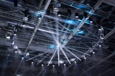 Sahne ışıkları. Performansın sahnesi projektörlerle aydınlatılıyor. Dumanın içinden bir ışık huzmesi geçiyor. Konserler ve spor sahaları için ışıklandırma ekipmanları..