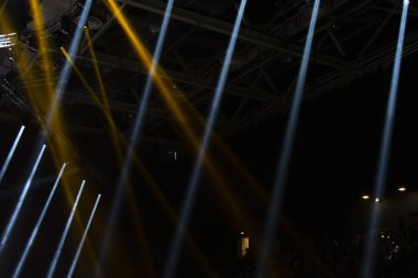 Sahne ışıkları. Performansın sahnesi projektörlerle aydınlatılıyor. Dumanın içinden bir ışık huzmesi geçiyor. Konserler ve spor sahaları için ışıklandırma ekipmanları..