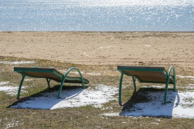 Kumsalda dinlenmek için boş güneş yatakları, plaj sezonunun kapanması, plajda ilkbaharın başlarında. Güneş parlıyor ve aydınlanıyor. Ölü sezon.