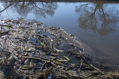 Nehirde yüzen çubuklar ve molozlardan oluşan baraj, çevre kirliliği, su manzarası, güneşli bir gün..
