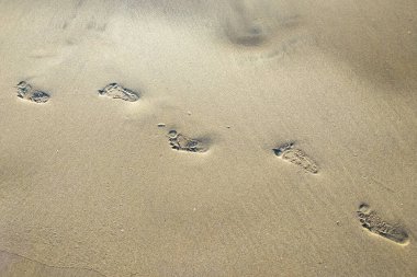 Sahilde çocukların ayak izleri gri kumlar, deniz dalgaları, plajlar ve dinlenme yerleri tarafından yıkanmış..