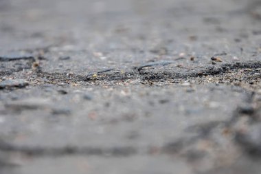 Şehirdeki çatlak asfalt, yoldaki çatlaklar ve çukurlar, desenli yol yüzeyi, seçici odaklanma..