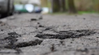 Şehirde çatlak asfalt, yolda çatlaklar ve çukurlar, bir insan geçiyor, ateş etmenin alt noktası, ufuk çizgisi görünür, seçici odaklanma.