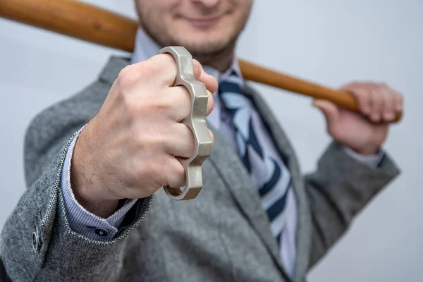 Metal knuckles in a man\'s hand, a wooden bat behind his back, a prohibited weapon in a fight, a heavy blow, street thugs, urban gangs of robbers.