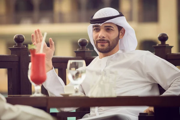 Um árabe está a beber café num café. Ele se senta a uma mesa em um c — Fotografia de Stock