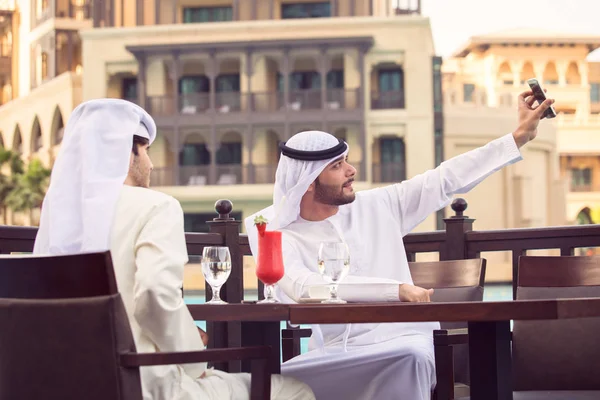 Zwei arabische Männer machen ein Selfie in einem Café und trinken roten Saft bei d — Stockfoto