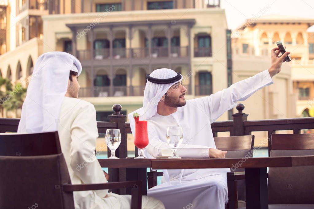 two Arab man taking a selfie in a cafe, and drink red juice at D