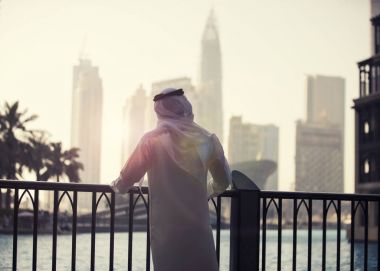 Arap adam seyir için Dubai şehir silüetinin akşam zaman 