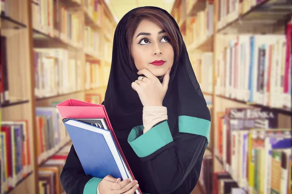 Arapça öğrenci kitaplığa bir kitap tutan hijab giyen 