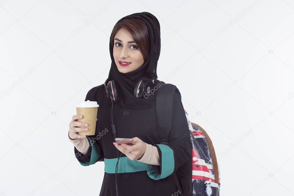arab student wearing hijab holding mobile and coffee cup 