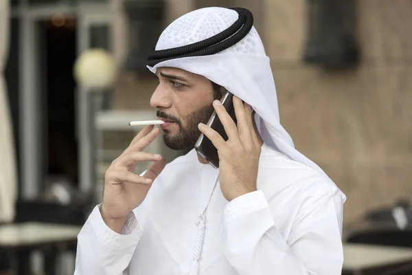 Jeunes hommes arabes fumant un cigare, tout en parlant au téléphone — Photo