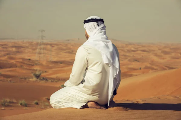 Hombre árabe emiratí sentado en la cima de una duna en el desierto de los EAU — Foto de Stock