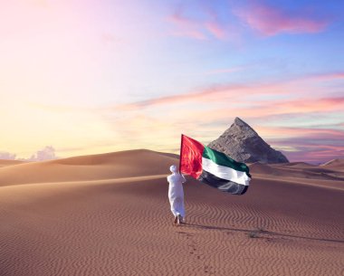 Çölde yürüyen Emirati adamı Uae bayrağını tutuyor. Ulusal günü kutluyor.